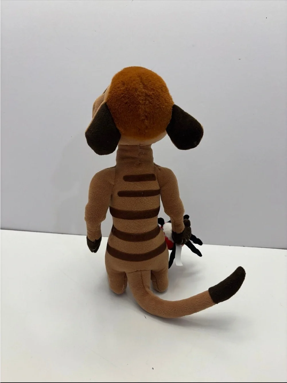 Disney The Lion King Timon plush toy holding a small red ladybug